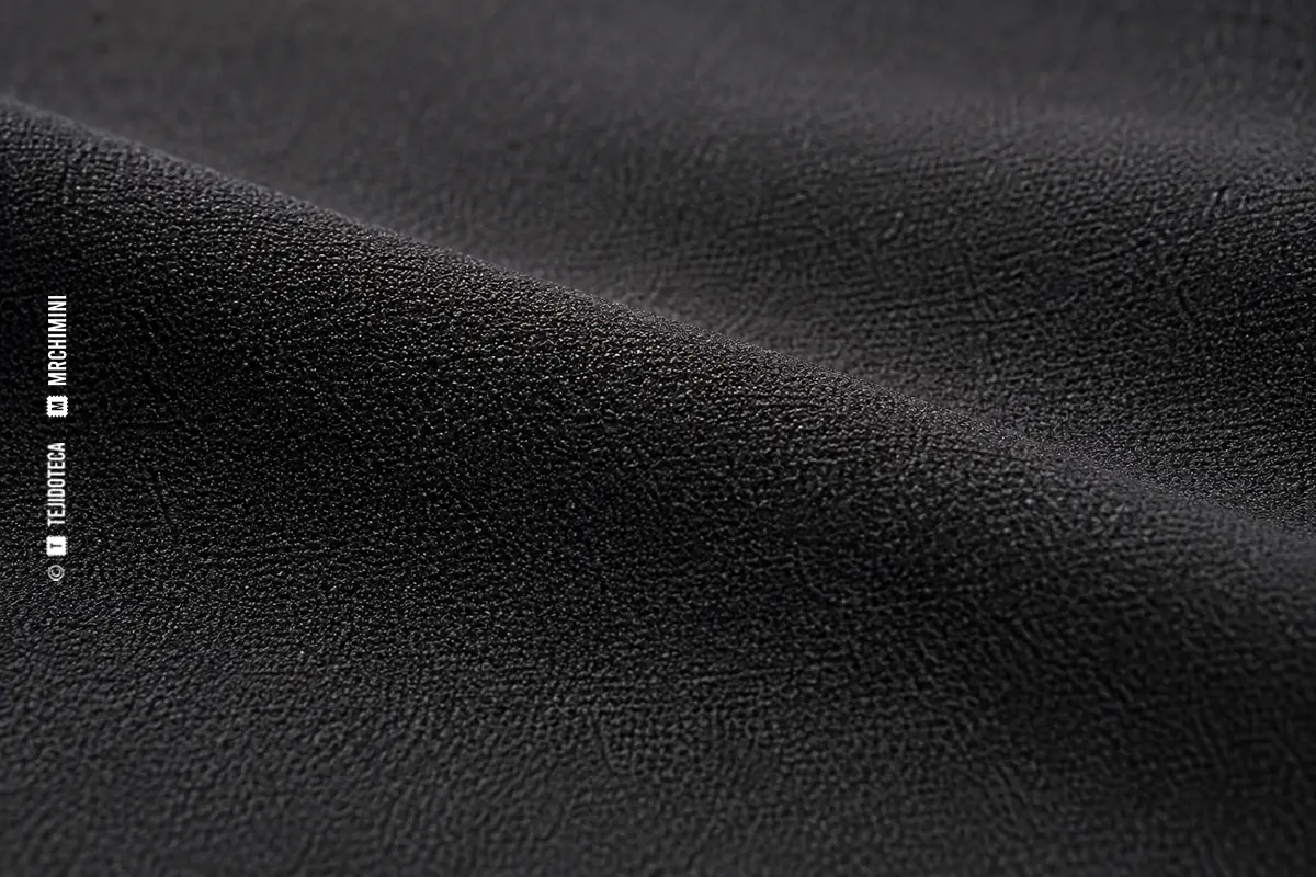 Macrofotografía de tejido crepé negro con superficie granulada y mate
