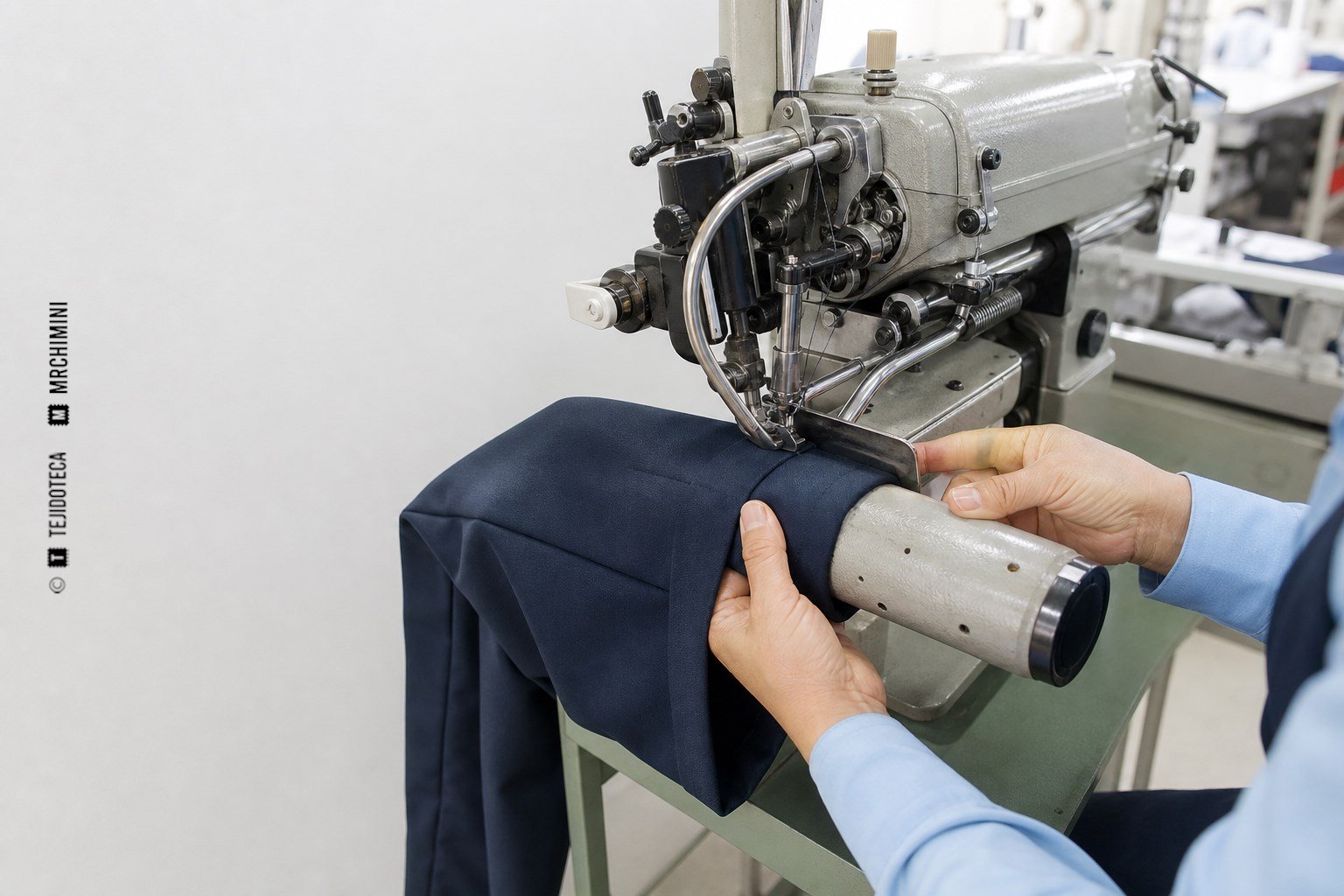 Máquina industrial formando y cosiendo el bajo de una pernera de pantalón