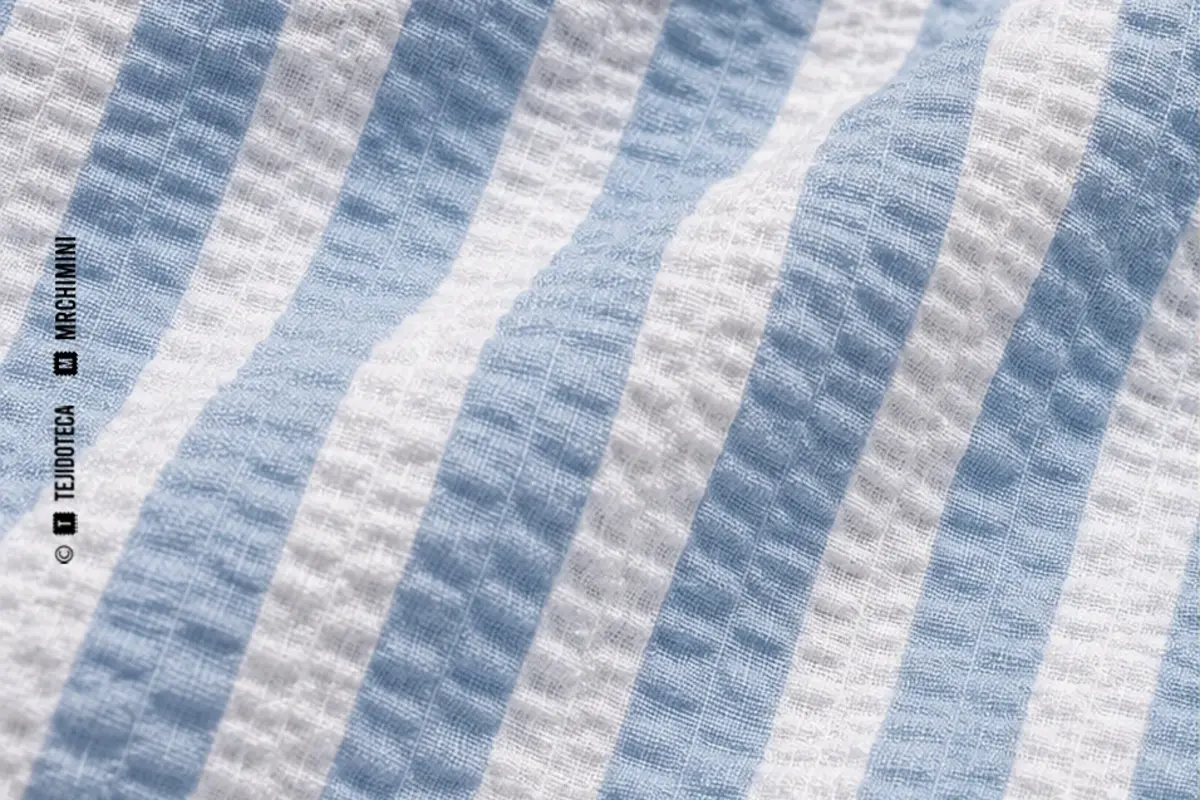 Macrofotografía de tejido seersucker en rayas azul cielo #7EA8C4 y blanco