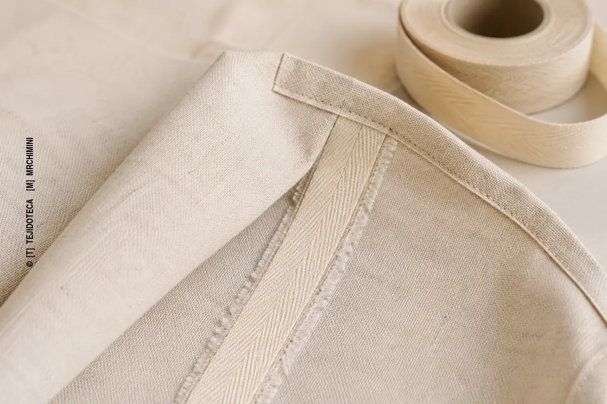 TAPACOSTURAS – detalle macro Interior de una pieza textil con una cinta tapacosturas aplicada sobre los márgenes de una costura.