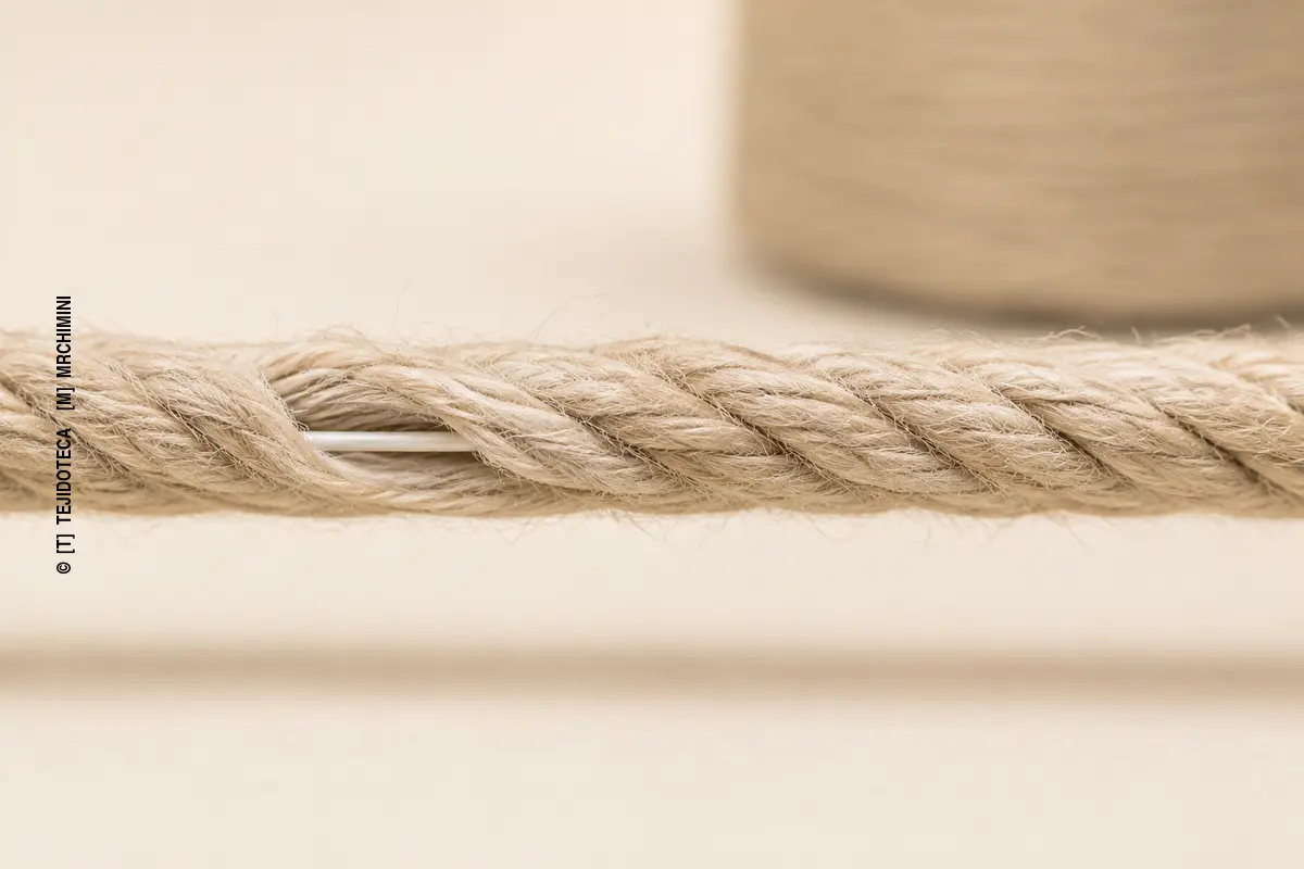 Detalle macro de un hilo con alma que muestra un fino núcleo continuo rodeado por fibras discontinuas hiladas.