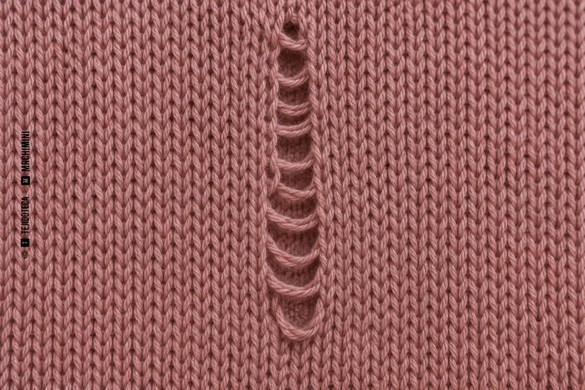 Macro de jersey rosa con una columna de mallas deshecha verticalmente