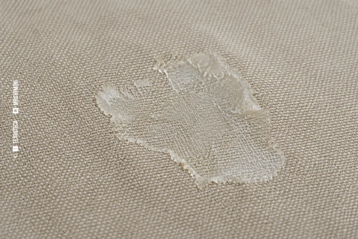 MANCHA DE PRODUCTO DE ACABADO en un tejido depósito seco semitransparente de producto sobre tejido beige — TEJIDOTECA
