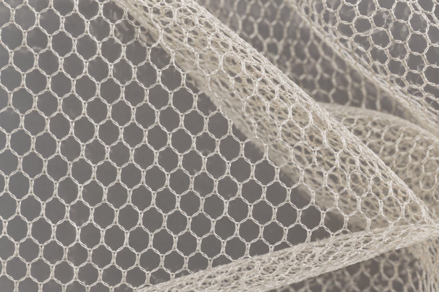 Detalle macro de bobineta de algodón marfil con malla hexagonal estable