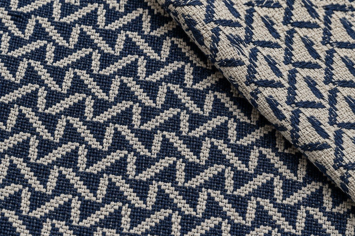 Macro de jacquard geométrico azul marino y marfil con una esquina vuelta que muestra la distribución de hilos del reverso