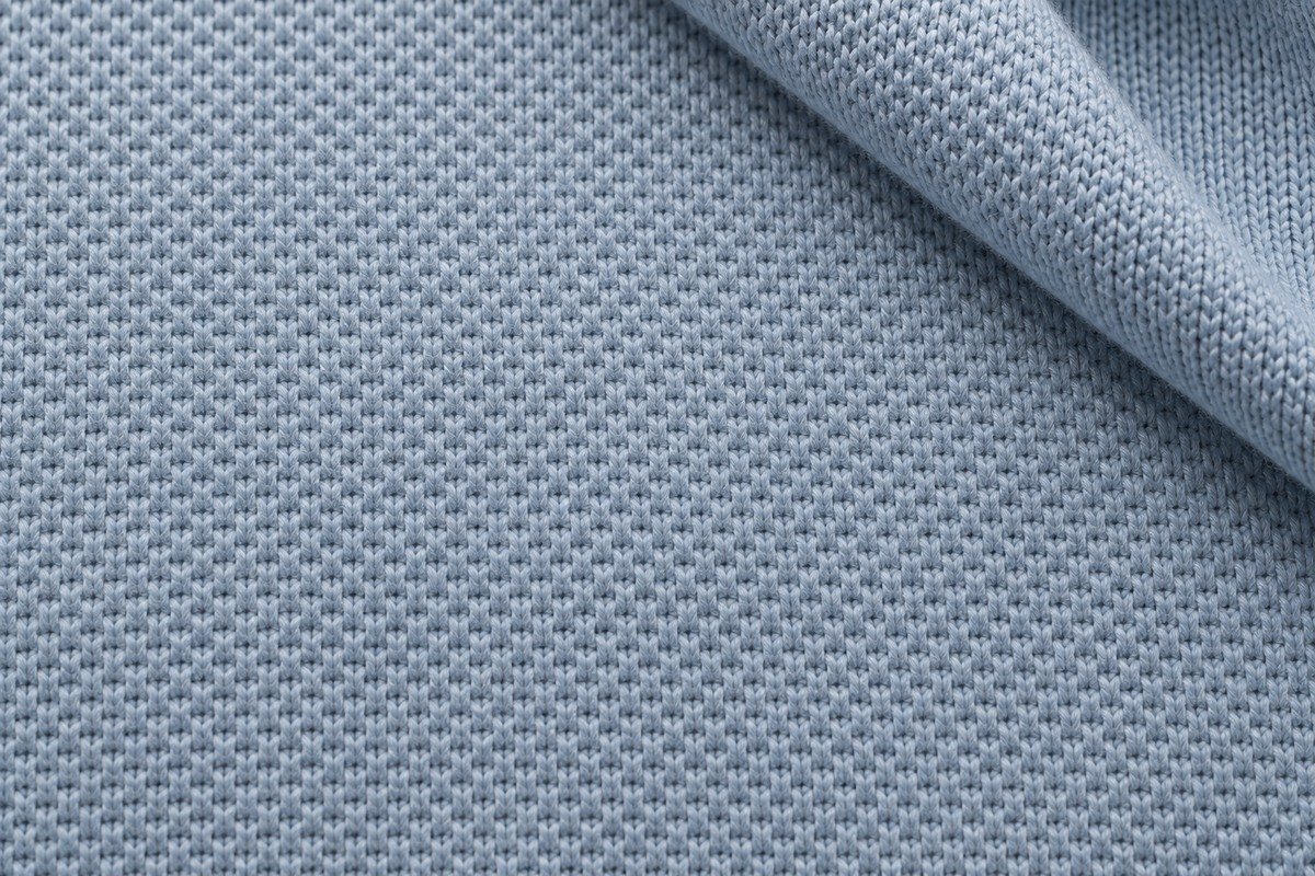 Macro de piqué de punto azul con pequeños relieves y una esquina doblada que muestra la otra cara