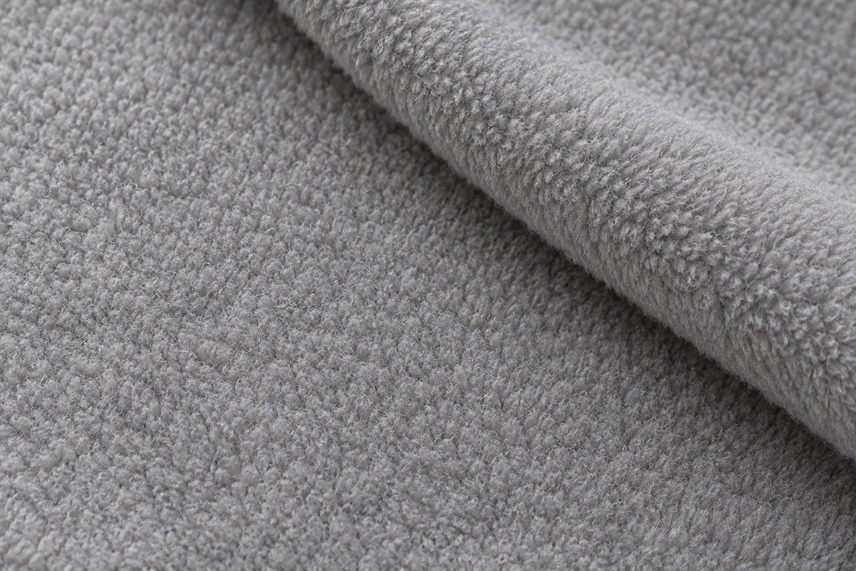 Detalle ampliado de polar gris con pelo corto en ambas caras y una esquina doblada que permite compararlas