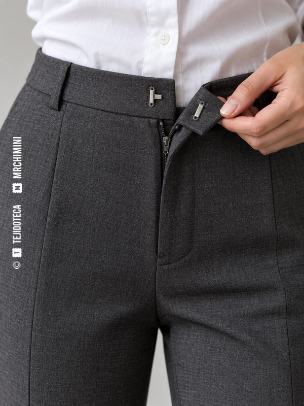 Cinturilla de pantalón gris abierta para mostrar un cierre plano de gancho y barra.