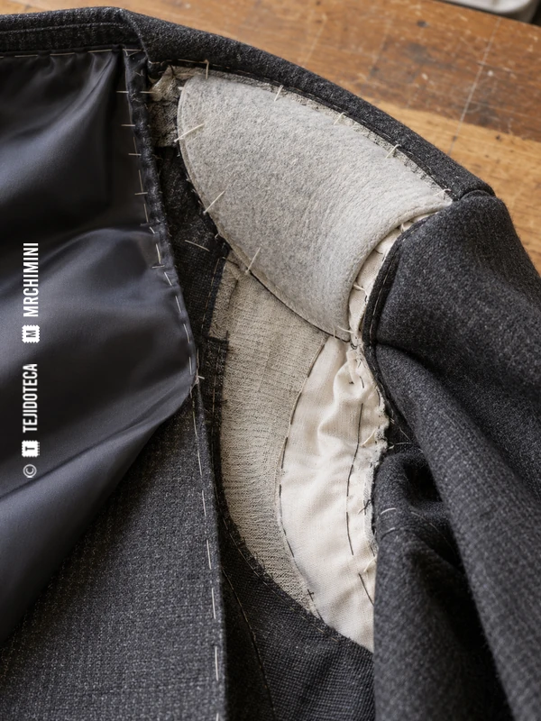 Interior de una chaqueta gris con la hombrera situada junto a la costura de hombro y la sisa.