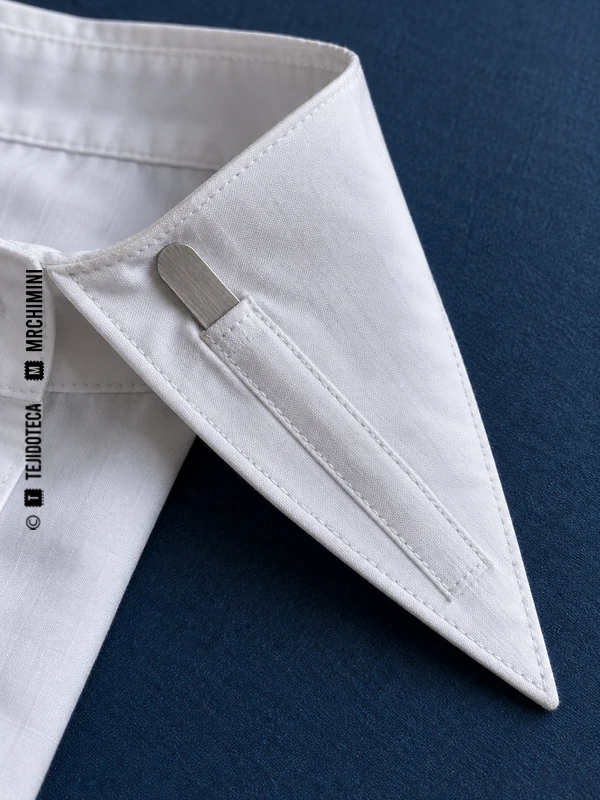 Revés de una punta de cuello de camisa con una varilla metálica parcialmente extraída de su funda.